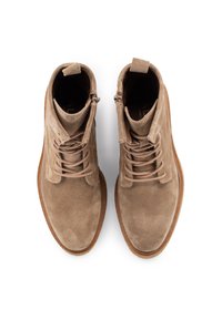 Botas de tobillo de ante marrón con cordones, punta redondeada, cremallera lateral y suela de goma marrón claro. Presenta costuras tonales sutiles y etiquetas.