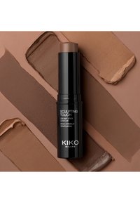 KIKO Milano Sculpting Touch kremet stikkontur, svart tube med hvit tekst, omkranset av prøver av brune og beige kremprodukter.