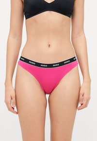 Culotte de bikini en coton rose avec une taille élastique noire portant le nom de la marque "HUGO" en lettres blanches. Ajustement et forme standards.