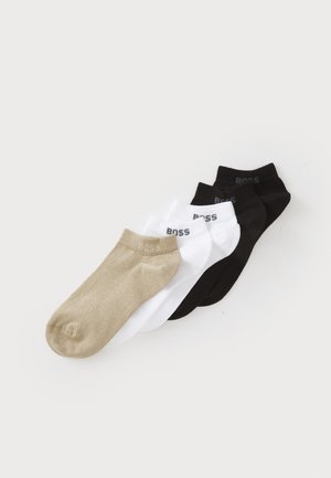 Four pairs of ankle socks: beige, white, and two black. Made of soft material, with a smooth texture and logo printed near the cuff.
