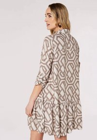 Beige Kleid mit geometrischem Muster, ausgestattet mit einem Kragen, knöpfbaren Ärmeln und einem Rüschensaum. Glatte Stofftextur.