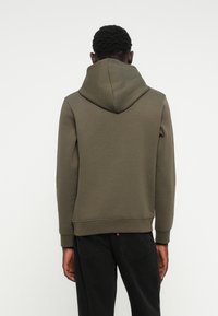 Hoodie vert olive en tissu texturé, avec poche kangourou, poignets côtelés et capuche à cordon, vu de l'arrière.