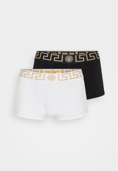 Două perechi de boxeri dintr-un material confortabil, una albă și cealaltă neagră, prezentând un model în colanții elastici inspirat de cheia grecească de culoare aurie și un detaliu al logo-ului în față.