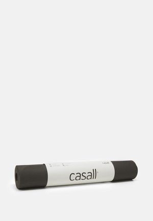 Esterilla de yoga negra enrollada, con una superficie texturizada para un mejor agarre y una etiqueta blanca con la marca "casall" a lo largo del lado.
