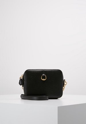 Sac bandoulière rectangulaire en cuir noir avec quincaillerie dorée et sangle amovible sur une surface blanche contre un fond blanc.