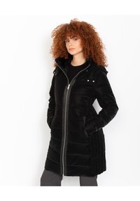 Abrigo acolchado negro con cierre de cremallera, bolsillos laterales y capucha. Hecho de material liso con textura acolchada y brillo sutil.