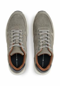 Szare zamszowe sneakersy z siateczkowymi akcentami, szarymi sznurówkami i białą gumową podeszwą. Brązowe wykończenie wokół kołnierza z logo marki w środku.