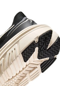 Scarpa da ginnastica nera con tomaia testurizzata e suola spessa in gomma beige con motivo a zigzag per una presa sicura.