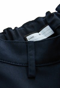 Tumesinine kangas, millel on tekstuuriga välimus. Omadusteks on kokkupandud kaelus ja rõivamärgisega nimeruumi koht.