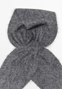 Écharpe grise et fluffy en matériau doux, présentant une texture légère avec une forme légèrement triangulaire et sans matériel ou motifs visibles.