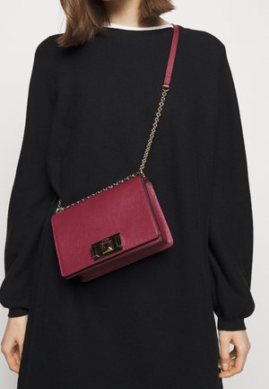 Borsa a tracolla in pelle color bordeaux con tracolla a catena e forma rettangolare, caratterizzata da una chiusura in metallo dorato e una finitura testurizzata.