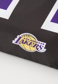 Sort sportsstof med "Los Angeles Lakers" logo i gult og lilla, med en basketball grafik og hvid omrids.