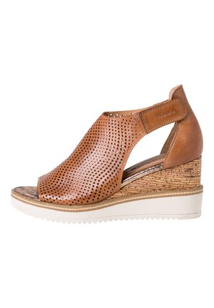 Sandale compensée en cuir marron perforé avec bout ouvert, talon à texture liège, semelle blanche et bride de cheville à velcro.