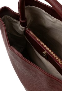 Borsa tote in pelle rossa testurizzata con interno a righe beige. Presenta due manici e un compartimento interno con cerniera.