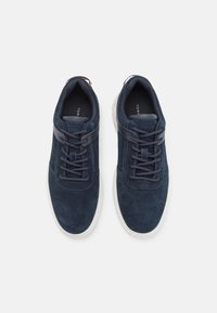 Adidași din suede bleumarin cu vârf rotund, talpă din cauciuc alb contrastant și șireturi tonale. Prezintă o etichetă de marcă la călcâi.