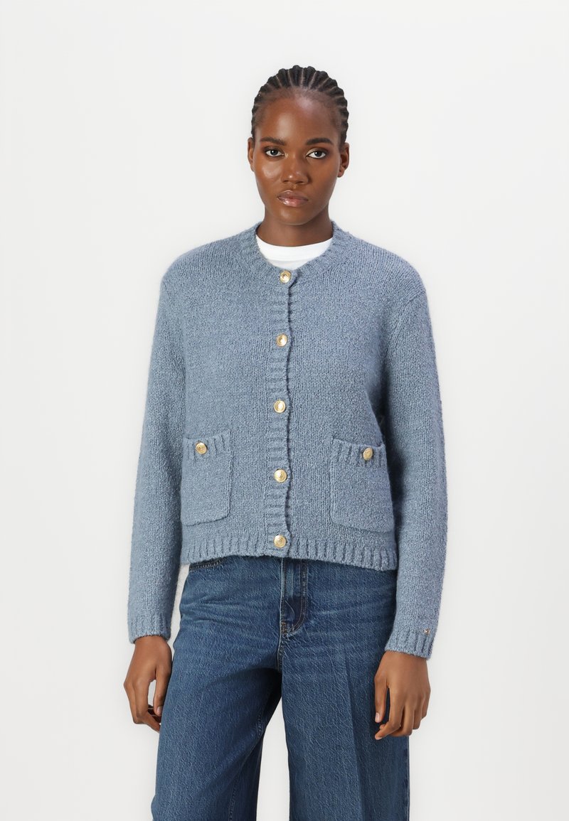  Lichtblauwe gebreide cardigan met een ronde halslijn, lange mouwen, twee voorke pocketen en gouden knoopsluitingen. Gestructureerde stof.