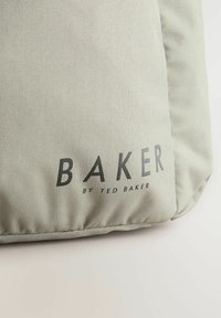 Sac gris texturé présentant le logo en relief "BAKER by TED BAKER" en noir. Le design est simple avec une finition lisse.