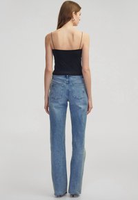 Lichtblauwe high-waisted jeans met een rechte pijp, gemaakt van denim. Bevat twee achterzakken en heeft een nette afwerking. Gecombineerd met een zwarte top.