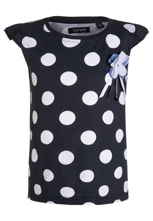 Chemise enfant bleu marine avec de gros pois blancs, manches courtes à volants, et une petite fleur décorative avec des rubans sur la poitrine.