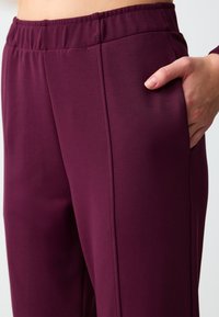 Bordeaux sportbroek van soepel stof, met een elastische tailleband en zijzak, voorzien van platte naden en een getailleerde pasvorm.