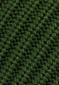 Dettaglio ravvicinato di un tessuto lavorato a maglia di colore verde scuro che mostra un motivo testurizzato di anelli intrecciati e fibre di filato morbide.