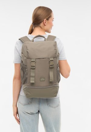 Khakifarbener Rucksack mit gepolsterten Trägern und obere Griff; verfügt über zwei Seitentaschen, eine Frontklappe und ein Logopatch vorne unten.