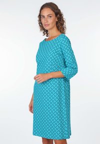 Türkises Kleid aus geometrisch gemustertem Stoff, mit rundem Ausschnitt und Dreiviertelärmeln, im lässigen Schnitt, das unter das Knie fällt.