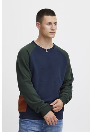 Marineblauwe sweatshirt met ronde hals en groene mouwen, met bruine zijaccenten, voorzien van ribgebreide manchetten en een relaxed fit. Soepele katoenen stof.