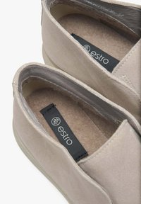 Béžové semišové nazouvací boty s kulatou špičkou, měkkou podšívkou a logem uvnitř. Mají flexibilní gumovou podrážku pro maximální pohodlí.