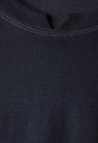 Mörkblå bomullstyg med ribbat mönster. Har en rundad halsringning med förstärkta sömmar, vilket ger en slät yta och jämn färg.