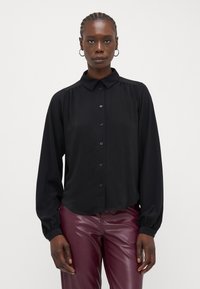 Camisa preta de botões com colarinho, mangas longas e detalhes franzidos. Feita de um tecido leve, apresenta um corte descontraído e um brilho subtil.