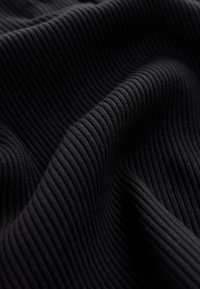 Tessuto nero a coste con superficie strutturata, caratterizzato da linee verticali che creano una serie di rilievi lungo tutto il materiale.