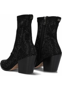 Botines negros hasta el tobillo con parte superior texturizada y adornos de strass. Tacones de bloque y cierre de cremallera lateral. Plantilla de cuero suave.