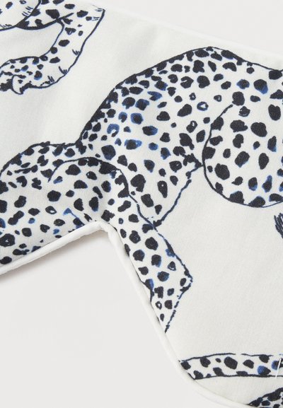 Λευκό ύφασμα με απεικονίσεις λεοπάρδαλων με μαύρες και μπλε κηλίδες, απαλή υφή, κοντινή λήψη που δείχνει τις άκρες και τα ραφιά στις γωνίες.