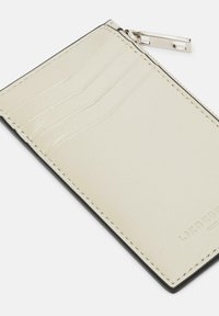 Kremowy skórzany portfel na karty z czarnym wykończeniem, wyposażony w cztery kieszonki na karty oraz przegrodę zapinaną na zamek. Gładka tekstura z przeszytymi krawędziami.