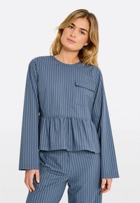 Blau gestreiftes Langarmoberteil mit Peplum-Saum, Rundhalsausschnitt und einer Brusttasche. Weicher Stoff mit glatter Textur. Kombiniert mit passenden Hosen.