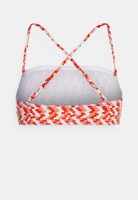 Bralette com padrões vermelhos e rosas, com design cruzado nas costas, alças ajustáveis e um forro interior suave. O material parece elástico.