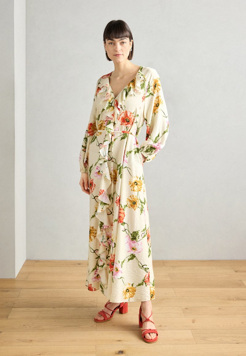 Abito maxi floreale in crema, con volant lungo lo scollo e le maniche, decorato con fiori rosa e gialli vivaci. Sandali a tacco blocco rossi.
