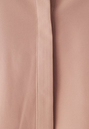 Tessuto rosa chiaro con una superficie texturizzata e modelli sottili. Sono visibili due sezioni di tessuto, unite da una cucitura.