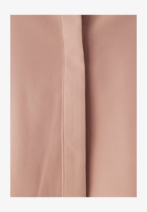 Lichtroze stof met een gestructureerd oppervlak en subtiele patronen. Twee delen stof zijn zichtbaar, verbonden door een naad.