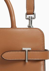 Borsa a tracolla in pelle color tan caratterizzata da un design strutturato, forma rettangolare, hardware in tonalità argento e una chiusura a patta con un bottone a forma di T.