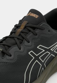 Black running shoe with textured upper, white logo, and orange accents. Features flat laces and a cushioned sole for comfort.