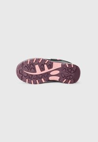 Suela de zapatilla deportiva en negro y gris con una superficie gruesa y texturizada que presenta acentos y detalles de goma en púrpura y rosa, así como tacos para mayor agarre.