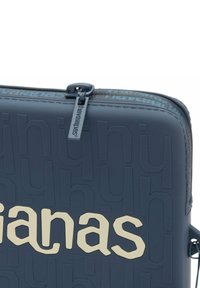 Borsa blu scuro con zip, caratterizzata da logo in rilievo, texture liscia e lettering di colore chiaro in contrasto. Mostra il dettaglio della cerniera.