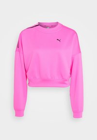 Felpa cropped rosa con maniche lunghe, caratterizzata da un logo nero sul petto e dettagli neri sulle spalle. Tessuto liscio e elastico.