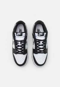 Baskets Nike noir et blanc. Tige en cuir, boîte à orteils perforée, lacets noirs plats, col rembourré et logo signature sur la languette et les côtés.