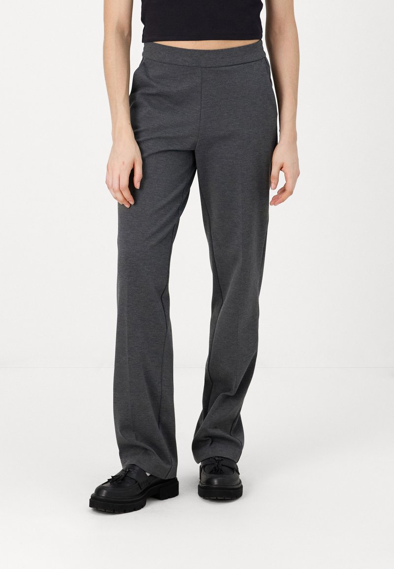 Pantalons gris, légers, extensibles avec un design à jambes larges et une taille élastique. Assortis à des chaussures noires à lacets épaisses.