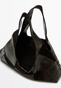 Leren shopper in donkerbruin met patchwork-ontwerp, voorzien van twee handvatten en een open bovenkant, met een gladde en gestructureerde oppervlakte.