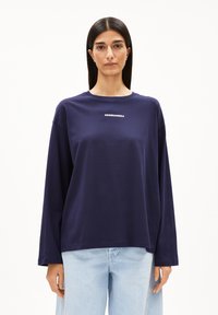 Navyblauwe longsleeve t-shirt met ronde hals en de tekst "ARMEDANGELS" in het wit. Gemaakt van een soepele stof met een ontspannen pasvorm en verlaagde schouders.