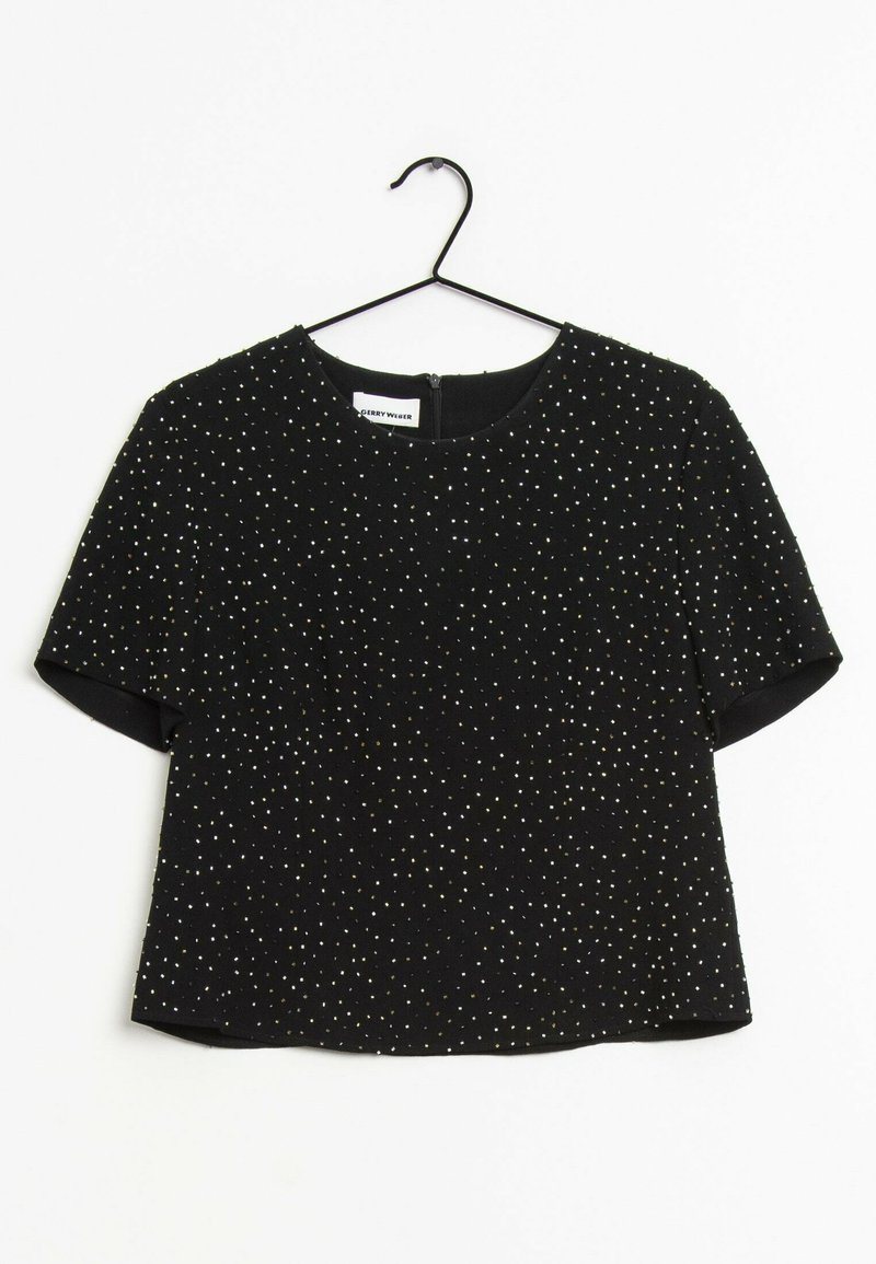 Top noir à manches courtes avec un col rond, arborant un motif de petits clous métalliques en argent et or. Fermeture éclair à l'arrière.